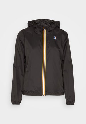 Veste légère noire avec une capuche, dotée d'une fermeture éclair centrale avec des bandes rouges, jaunes et blanches, et d'un logo sur la poitrine gauche.