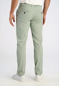 Chinos vert clair présentés de dos, dotés de deux poches arrière avec boutons et d'un tissu lisse légèrement texturé.