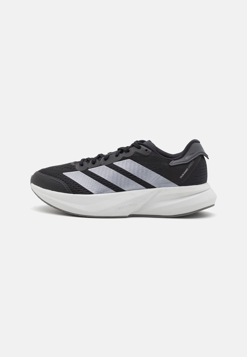 Schwarzer Sportschuh mit Mesh-Obermaterial, drei silberne Streifen an der Seite und einer weißen gepolsterten Sohle. Verfügt über eine strukturierte Außensohle für besseren Halt.