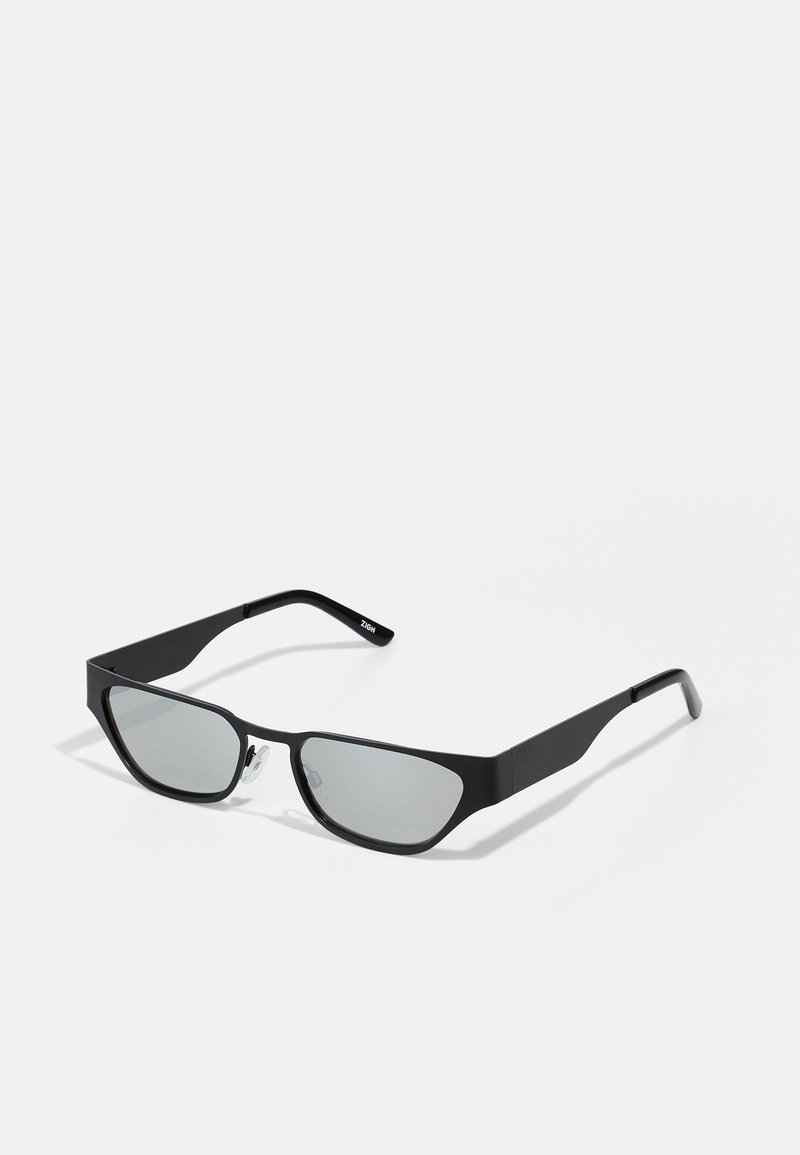 Óculos de sol pretos com lentes retangulares, acabamento mate e forma ligeiramente angular. Apresenta almofadas nasais transparentes e um design minimalista.