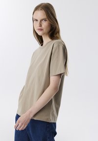 Beige katoenen T-shirt met ronde hals, korte mouwen, een relaxte pasvorm en een gladde textuur, gecombineerd met donkerblauwe spijkerbroeken.