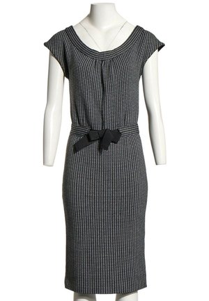 Robe mi-longue à motifs noir et blanc avec manches courtes et ceinture noire nouée à la taille sur un mannequin blanc.