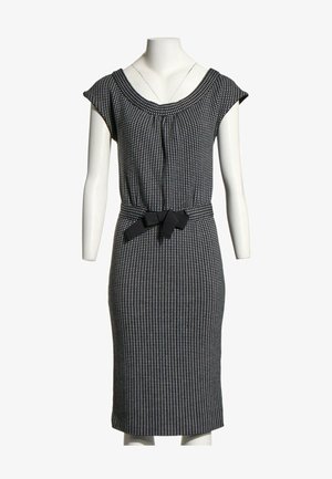Robe mi-longue à motifs noir et blanc avec manches courtes et ceinture noire nouée à la taille sur un mannequin blanc.