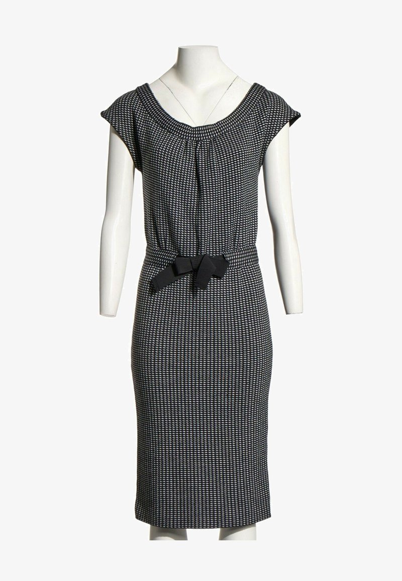Robe mi-longue à motifs noir et blanc avec manches courtes et ceinture noire nouée à la taille sur un mannequin blanc.