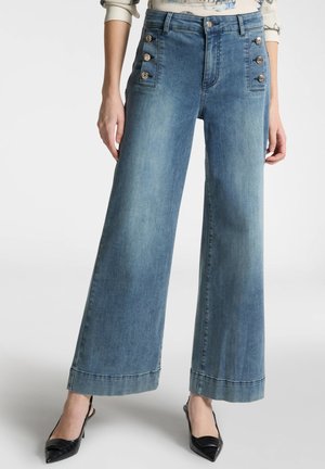 Pantaloni in denim a vita alta e gamba larga di colore azzurro, con bottoni decorativi ai lati, cuciture a contrasto e orlo dritto.