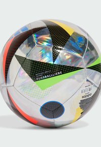 Replika míče Adidas s lesklým povrchem, zdobená barevnými geometrickými vzory v černé, žluté, zelené, červené a modré barvě.