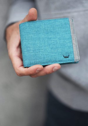 Blue fabric wallet with a textured finish, gray accent, and small logo detail. Held in a hand, showcasing its compact design.