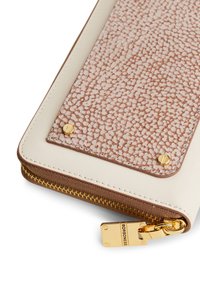 Brieftaschen-Ecke mit beigefarbenem Leder, strukturiertem braunem Paneel, das mit goldenen Schrauben befestigt ist, und einem goldenen Zipper-Puller, der mit "BORBONESE" graviert ist.