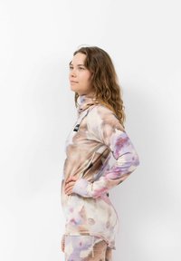 Langärmliges Oberteil aus einem leichten, strukturierten Stoff mit einem Aquarellmuster in sanften Rosa- und Brauntönen, mit hohem Kragen und figurbetontem Schnitt.