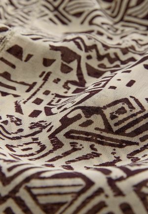 Beige fabric with a brown geometric pattern, featuring lines and shapes, showcasing smooth texture and subtle sheen.