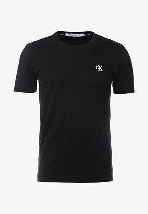 T-shirt noir à manches courtes avec col rond, petit logo blanc "cK" sur le côté gauche de la poitrine et étiquette "Calvin Klein Jeans" à l'intérieur du col.