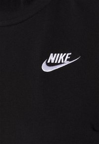 Černá textilie s žebrovanou strukturou, na které je bílé vyšití loga Nike. Design je jednoduchý a sportovní, zaměřený na viditelnost značky.