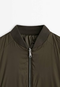 Khaki Bomberjacke mit geripptem Kragen, ausgestattet mit einem Frontreißverschluss und glatter, glänzender Textur. Keine sichtbaren Taschen.