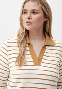 Striped long-sleeve top in cream and brown, featuring a v-neck with a contrasting collar. Textured fabric with visible ribbing.