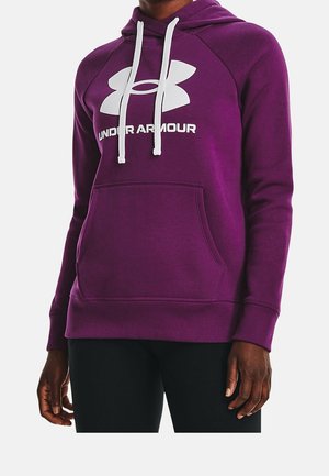 Personne portant un sweat à capuche Under Armour violet avec des cordons blancs et une poche kangourou à l'avant, visible de la poitrine jusqu'aux hanches.