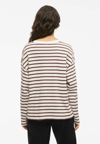 Langermet t-skjorte i krem med burgunder striper, med en avslappet passform, rund hals og senkede skuldre. Glatt tekstur og uformelt design.