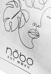 Zilver gestructureerd materiaal met een zwarte lijntekening van een gezicht en plantbladeren. Bevat de merknaam "nōbo" en "EST MMXV" onderaan.