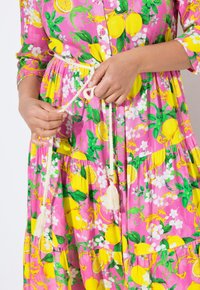 Abito floreale rosa con limoni gialli, foglie verdi e accenti bianchi. Include una cintura con corda annodata con nappine e dettagli con bottoni.