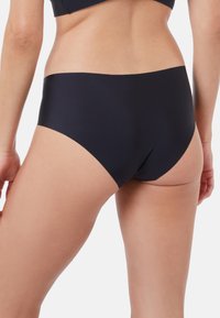 Schwarze Unterwäsche mit einem glatten, elastischen Design, moderatem Bund und nahtlosen Kanten für hohen Tragekomfort. Der Stoff wirkt weich und flexibel.