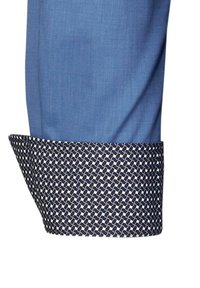 Manica di camicia blu con polsino a motivi blu navy e bianco. Il polsino presenta una texture intrecciata, mentre il tessuto principale ha una finitura liscia.