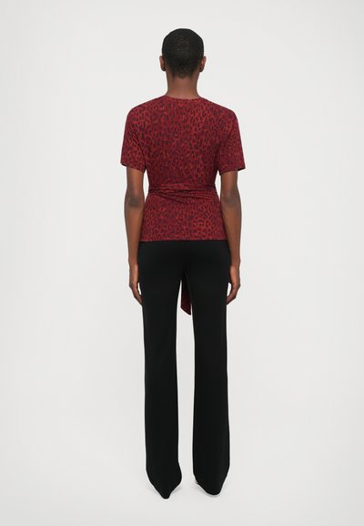 Rode luipaardprint top met korte mouwen, aansluitend ontwerp en zijstrikdetail, gecombineerd met zwarte flared broek. Gladde textuur, casual stijl.