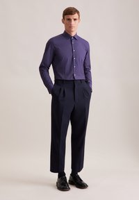 Camicia a bottoni a maniche lunghe con motivo viola abbinata a pantaloni eleganti a vita alta di un blu navy scuro e scarpe stringate nere.