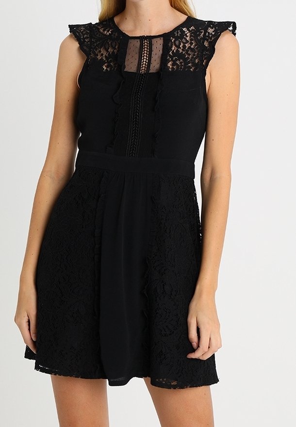 Robe noire sans manches avec empiècement en dentelle, bordure à volants et panneaux en dentelle sur la jupe, taille cintrée, longueur genou.