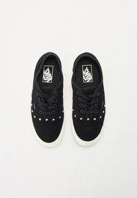 Black suede sneakers feature silver studs along the upper, rounded toe, laces, and a white rubber sole with logoed insoles.