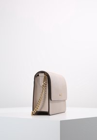 Borsa a tracolla in pelle beige chiaro con una tracolla a catena dorata, forma rettangolare, chiusura a pattina e rifiniture scure. La texture appare liscia con una leggera lucentezza.
