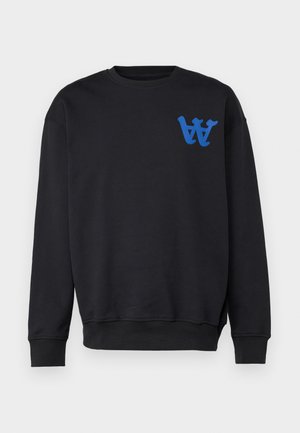 Must must shirt, mille sinistal sinine logo, koos mustade pükstega ja valgete sporditossudega. Sile kangas, mugav lõige.