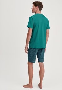 Turquoise short-sleeve t-shirt paired with patterned blue swim shorts featuring a wave design, constructed from lightweight fabric.