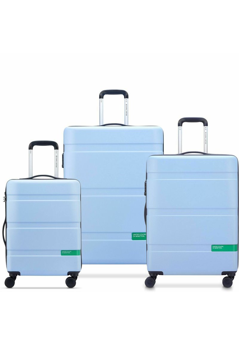 Three hard-shell suitcases in light blue, varying in size. Each features horizontal grooves and green branding accents. Retractable handles and wheels.