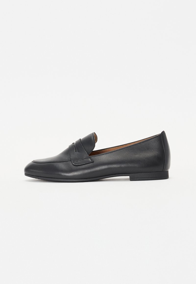 Mocassins en cuir noir avec un bout arrondi, des accents de couture proéminents et une semelle en caoutchouc basse. Texture lisse sans embellissements visibles.