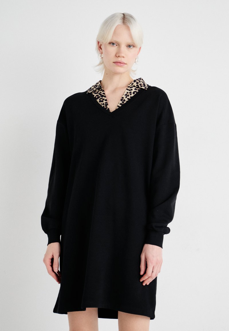 Čierne oversized šaty s dlhými rukávmi a výstrihom do V, s golierom s leopardím potlačou. Vyrobené z mäkkej, textúrovanej látky.
