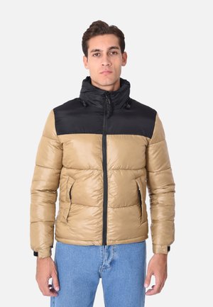 Giacca a vento in beige e nero, con chiusura a zip, colletto alto e tasche laterali. Texture liscia e lucida con design trapuntato.
