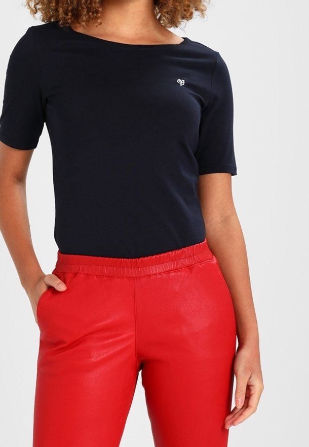 Navy short-sleeve top with a round neckline, featuring a small logo. Paired with red faux leather elastic-waist pants.