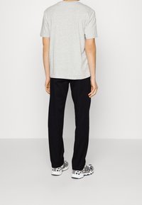 Grå bomulds t-shirt kombineret med sorte bukser og atletiske sko. T-shirten har en klassisk rund hals og korte ærmer.