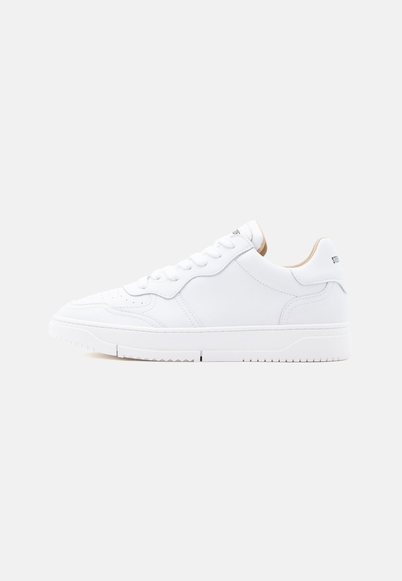 Λευκό sneaker από δέρμα με χαμηλή γραμμή, κορδόνια στο μπροστινό μέρος και εσωτερική επένδυση σε μπεζ, εμφανίζεται σε πλευρική όψη σε απλό φωτεινό φόντο.