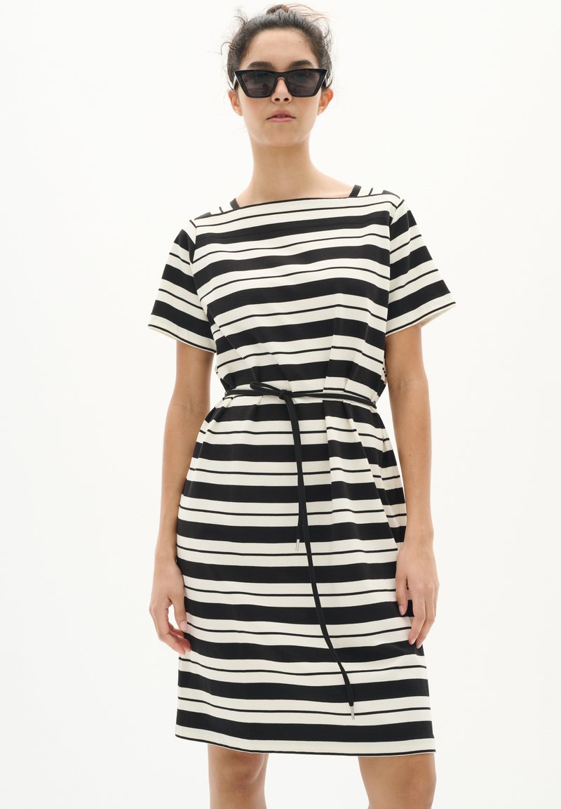 Abito a righe in bianco e nero con maniche corte, vestibilità comoda, vita cintrata e cintura da annodare. Tessuto liscio con righe a contrasto.