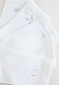Białe bawełniane skarpetki ozdobione srebrnymi cyrkoniami w kształcie serca, kwiatu, buźki i abstrakcyjnych wzorów, o prążkowanej fakturze i z falbankowymi krawędziami.