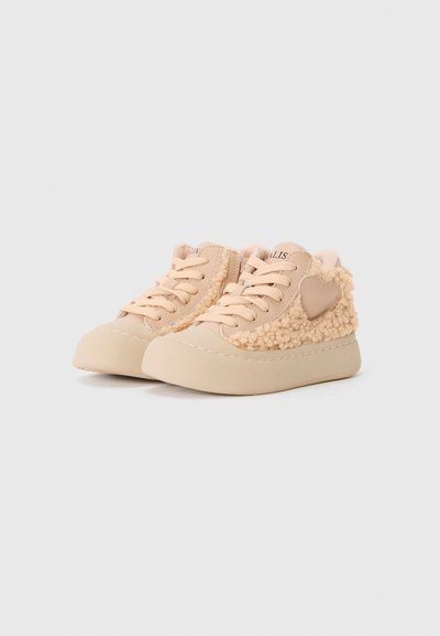 Beige babysko med myk, teksturert pels på sidene, snøring, avrundet front og hevet plattformsåle.