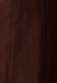 Rjav material z teksturirano tkanjem, ki prikazuje vidne šive in gladko površino, z globoko, bogato barvo in doslednim odtenkom.