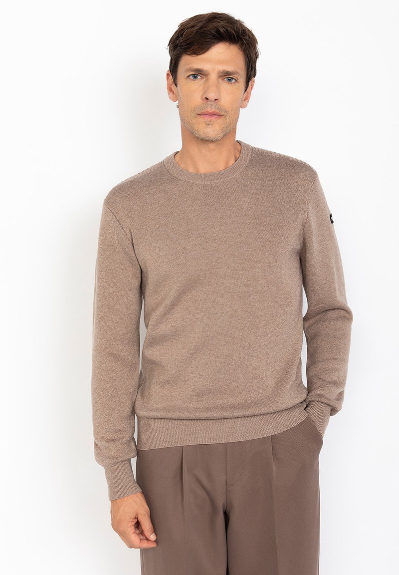 Brązowy sweter z okrągłym dekoltem, wykonany z miękkiego materiału dziewiarskiego, z prążkowanymi mankietami i dołem, z akcentem logo na lewej rękawie.
