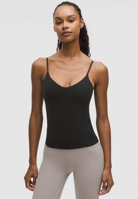 Black tank top with thin straps and a V-neck design, made from a smooth material. Worn with light-colored, fitted leggings.