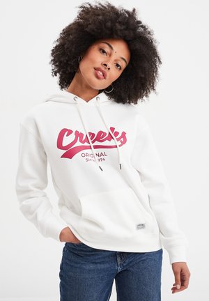 Witte hoodie met een groot rood logo "Creek's Original Since 1974" gedrukt op de voorkant, met een buidelzak en een capuchon met trekkoord.