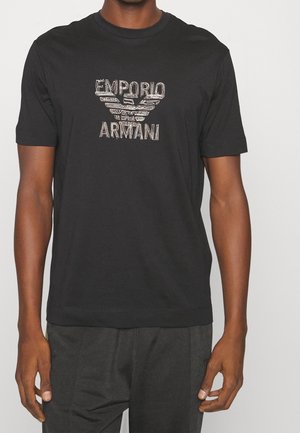 Schwarzes Baumwoll-T-Shirt mit aufgedrucktem "Emporio Armani"-Logo und Adlerdesign. Kurze Ärmel und Rundhalsausschnitt. Klassische Passform.