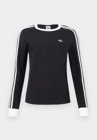 Čierna košeľa s dlhým rukávom, bielym golierom a manžetami, bielymi pruhmi pozdĺž rukávov a malým bielym logom Adidas na ľavej hrudi.