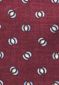 Bordowa tkanina z powtarzającym się wzorem niebieskich i kremowych owalnych kształtów z ciemnym konturem, tworząca teksturowany, dwukolorowy wzór.