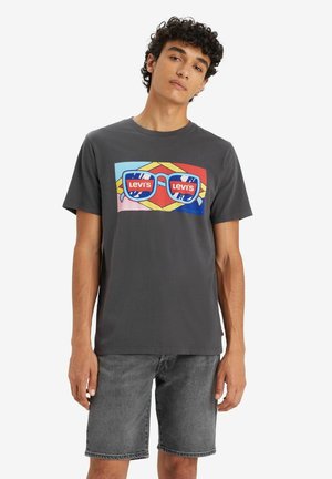 T-shirt en coton gris avec un graphique coloré de lunettes de soleil et le texte "Levi's", associé à un short en denim gris assorti.