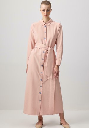 Lange roze jurk van lichte stof, met een knoopsluiting aan de voorkant met blauwe knopen, lange mouwen en een strikriem om de taille.